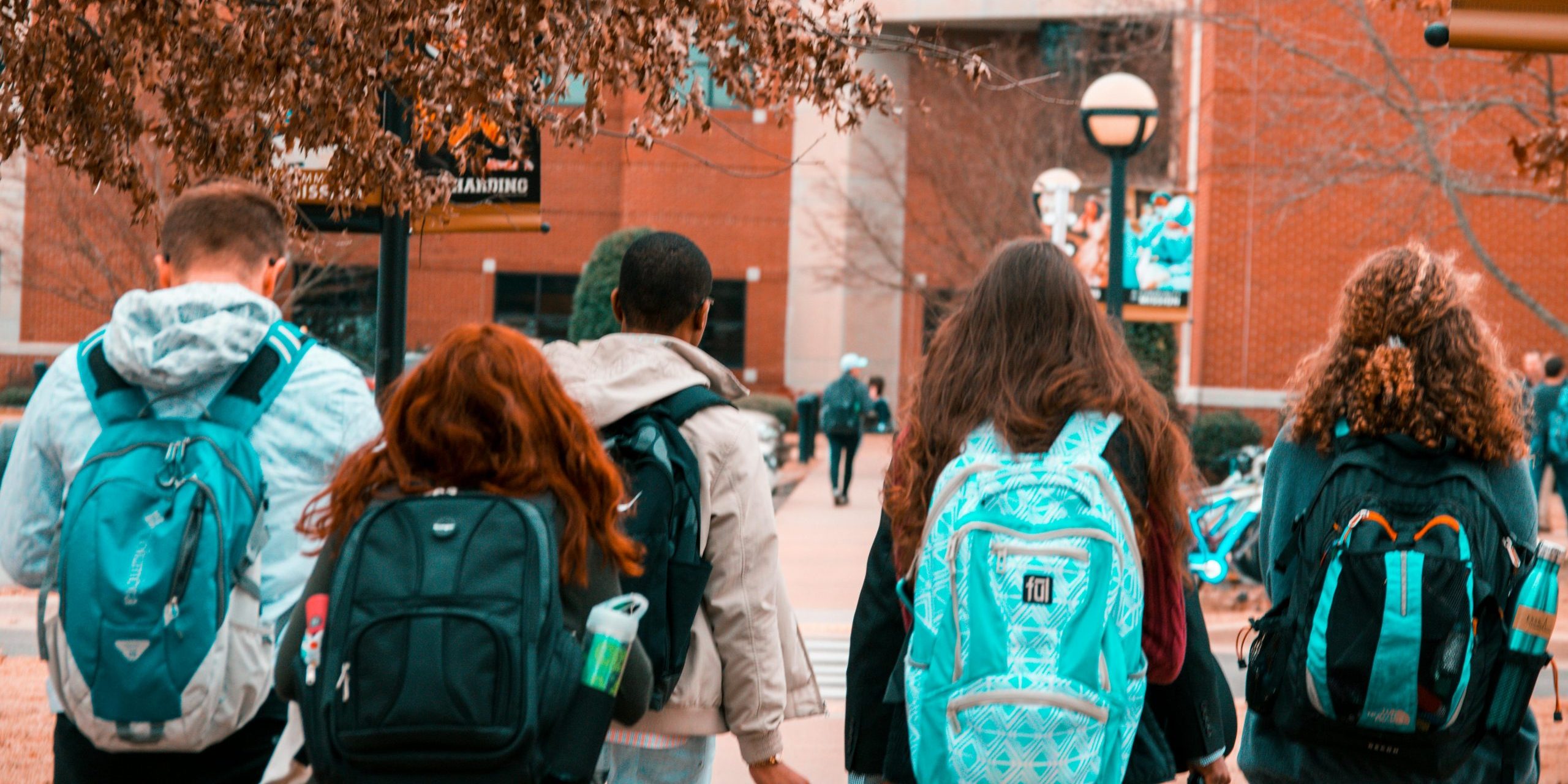 A group of college students with backpacks walking together outdoors on campus.