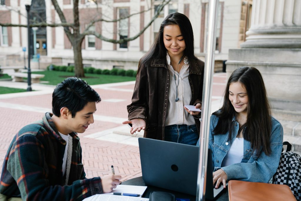 Group of university students collaborating and studying together in an outdoor setting.