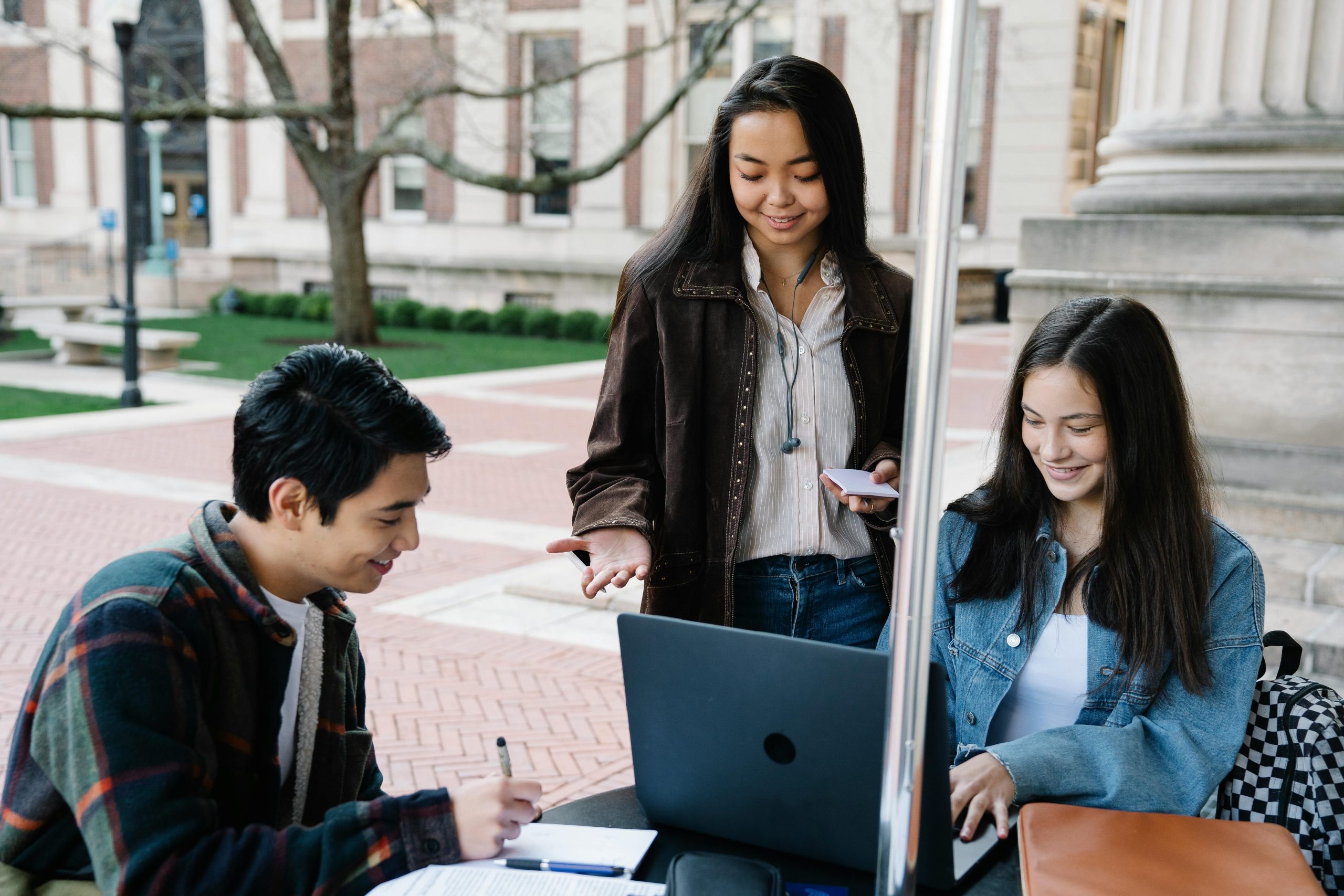 Group of university students collaborating and studying together in an outdoor setting.